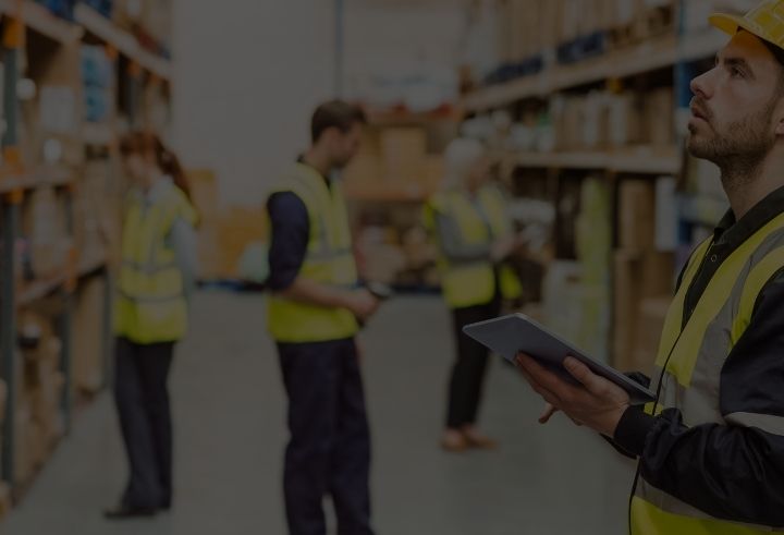Warehouse work team wearing high visibility clothing in a warehouse looking at inventory with a rugged tablet